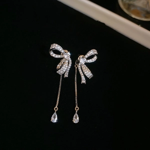 Macro shot of silver bow stud earrings with sparkling tassel and teardrop crystal drops