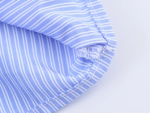 Detail shot of blue and white striped cotton shirt showing refined hem stitching craft
