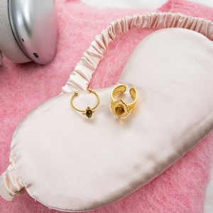 Detail showing gold twist and layered rings with tiger eye stones on pink silk cloth