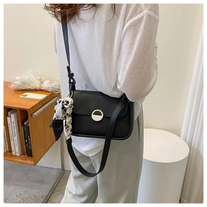 Close-up of black leather crossbody bag with gold lock and decorative silk scarf accessory