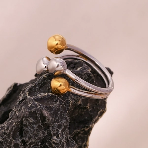 Detail of two-tone 18K gold plated stainless steel ring on dark natural stone