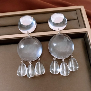Detailed view of large transparent resin drop earrings on a brown jewelry display box