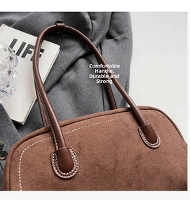 Detailed close-up of brown suede bag handle with white contrast stitching and soft texture
