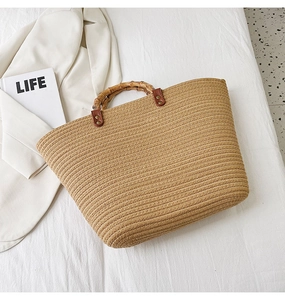 Detailed view of woven straw tote bag with bamboo handles and chic leather buckle