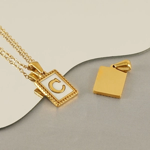 Makroaufnahme Goldanhänger mit weißem Inlay und goldenem Buchstaben C Detail