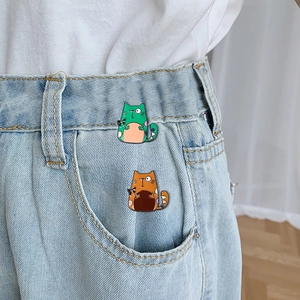 Creative cartoon cat enamel brooches in green and orange pinned on denim pockets