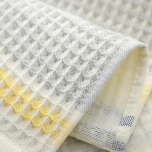 Detailed macro view of waffle weave cotton towel texture with yellow and blue stripes