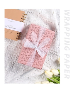 Pink wrapping paper with golden honeycomb texture and a white lace bow on a gift box