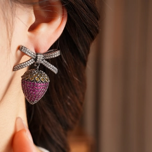Macro shot of a strawberry bow earring with pink zircon stones worn by a model