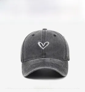 Detailed embroidery of white heart pattern on washed grey denim baseball cap
