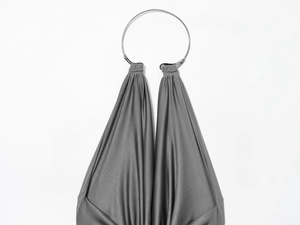 Detail of grey pleated halter dress featuring a large silver metal ring on silky fabric