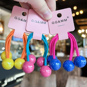 Close-up of three colorful hair ties with round beads on a pink display card