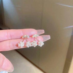 Detail of cherry-shaped stud earrings featuring gold leaves and white pearl berries