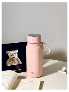 Detailed macro of pink matte stainless steel bottle with tea infuser on a lifestyle desk