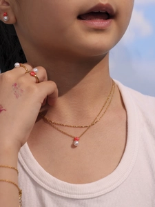 Vista detallada de niña con conjunto de joyas de estrella de mar roja y perlas con collar