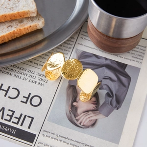 Dettaglio del bracciale dorato martellato su un giornale vintage con caffè e luce