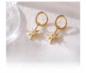 Detailed view of gold octagonal star titanium steel earrings with white zircon on fabric