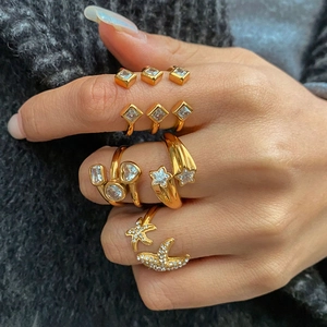 Close-up of model wearing stacked gold stainless steel rings with zircon starfish and heart