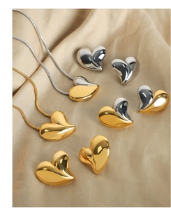 Détail de pendentifs cœur bicolores et boucles d'oreilles sur tissu en soie beige