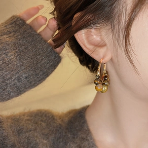 Detailed close-up of tiger eye beaded C-shape earrings worn for an aesthetic look