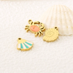 Macro shot of gold ocean pendants featuring crab and seashells with enamel details