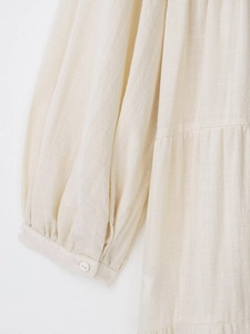 Detail of cream cotton-linen dress featuring a single-button cuff and textured fabric
