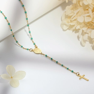 Detail of gold rosary necklace with green beads, a religious medal, and a cross pendant