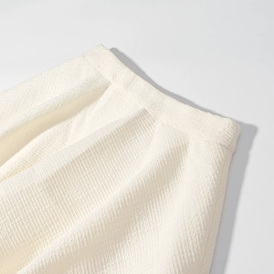 Dettaglio della trama in tweed crema elegante e finitura della vita della gonna