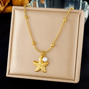 Detail van de gouden zeester hanger met witte parel aan een delicate schakelketting
