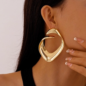 Close-up of oversized gold irregular hollow earrings with a smooth metallic texture
