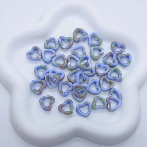 Detail of blue and green ink marble ceramic heart beads in a white star tray for DIY jewelry