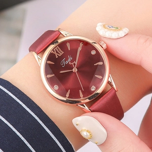 Close-up of elegant red quartz watch with Roman numerals and rhinestone dial