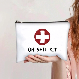 Detail of white canvas OH SHIT KIT pouch with red cross icon and secure black zipper