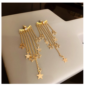 Macro detail of gold star tassel earrings with rhinestone bars and hanging chains