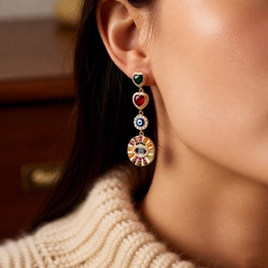 Detail view of vintage asymmetric drop earring with heart stones and evil eye motif