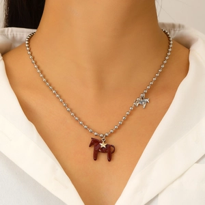 Nahaufnahme der roten Emaille-Pony- und Goldstern-Anhänger an einer silbernen Perlenkette