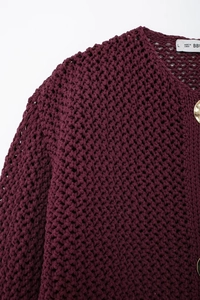 Close-up of wine red chunky knit cardigan with gold buttons and hollow out texture