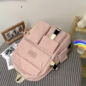 Pink multi-pocket canvas backpack with adjustable straps on a stylish stool for students