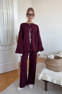 Detail of burgundy knit cardigan set and high-waist trousers on a lifestyle indoor model