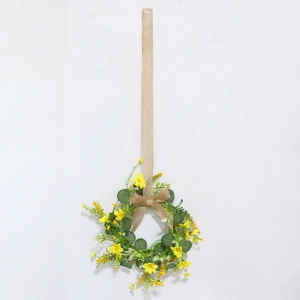 Detail of yellow flower wreath with green leaves and a rustic jute burlap bow hanger