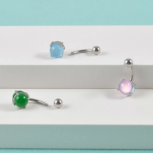 Three-piece set of 14G stainless steel belly rings with colorful round stones on white stand