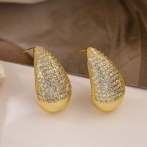 Detalle de pendientes de gota dorados con circonitas pavé brillantes y acabado pulido