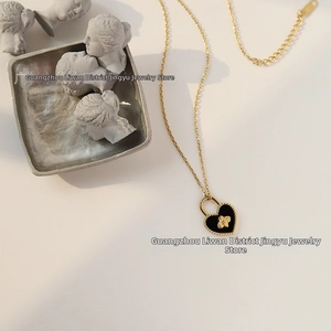Detail showing the heart-shaped black enamel pendant with golden bee relief on a fine chain