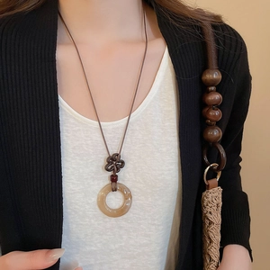 Close-up of translucent amber resin ring pendant necklace with vintage knot detail