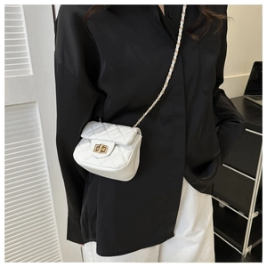 Detailed side view of white quilted mini crossbody bag with gold chain on model
