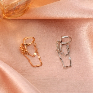 Detailaufnahme von Gold und Silber Stern-Ohrklemmen mit Ketten auf rosa Seidenstoff