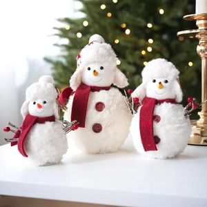 Trois figurines de bonhomme de neige en peluche avec écharpes rouges et lumières bokeh