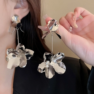 Detailed shot of large silver flower tassel earrings with glossy metallic finish