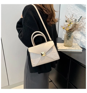 Gros plan du sac en similicuir blanc cassé avec motif croco et fermoir pyramidal doré