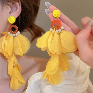 Close-up of yellow fabric flower petal drop earrings with orange rings on a model